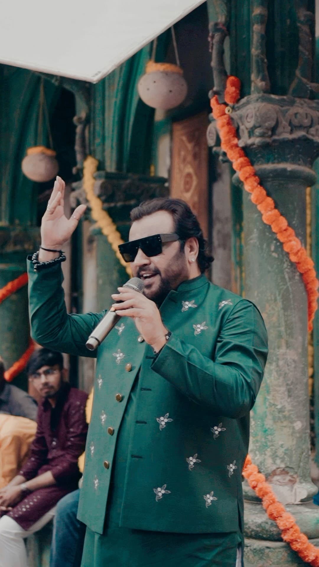 Kirtidan Gadhvi on stage in a green kurta under festive lights