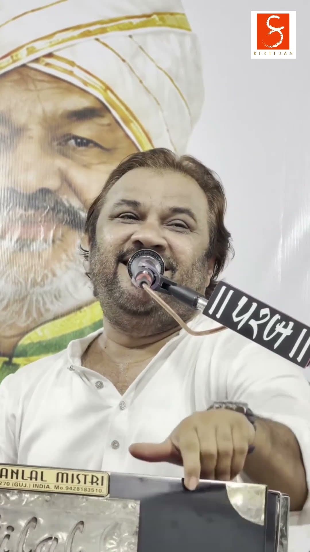 Kirtidan Gadhvi smiling at the harmonium