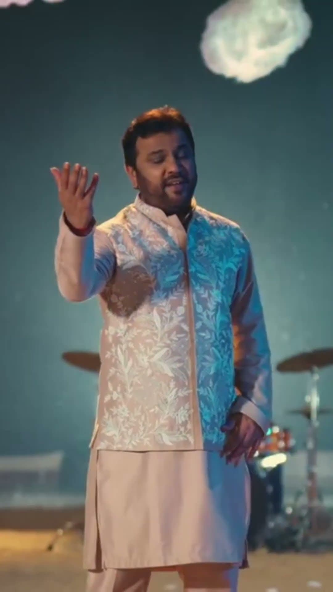 Kirtidan Gadhvi singing on stage in a white kurta
